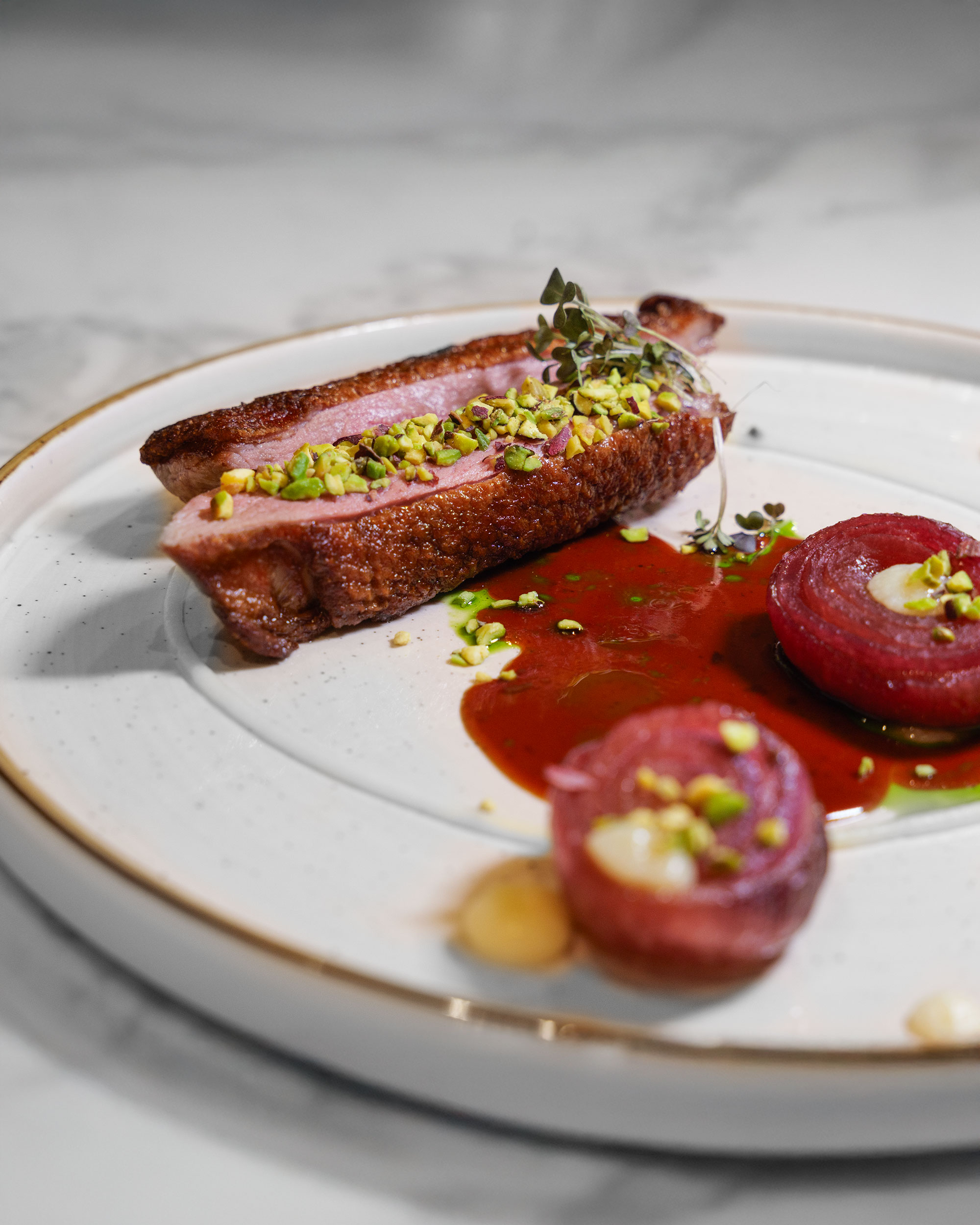 Anatra, crema di topinambur, pistacchio, cipolla rossa caramellata ed erbette.